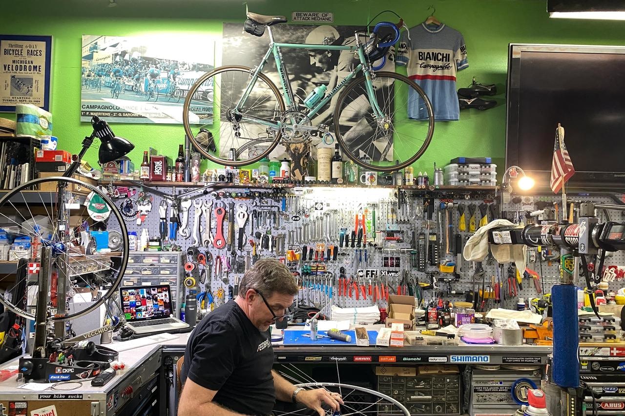 Jim Potter, the shop owner, works on a wheel in front of his work stand and a 1981 Bianchi from his person collection